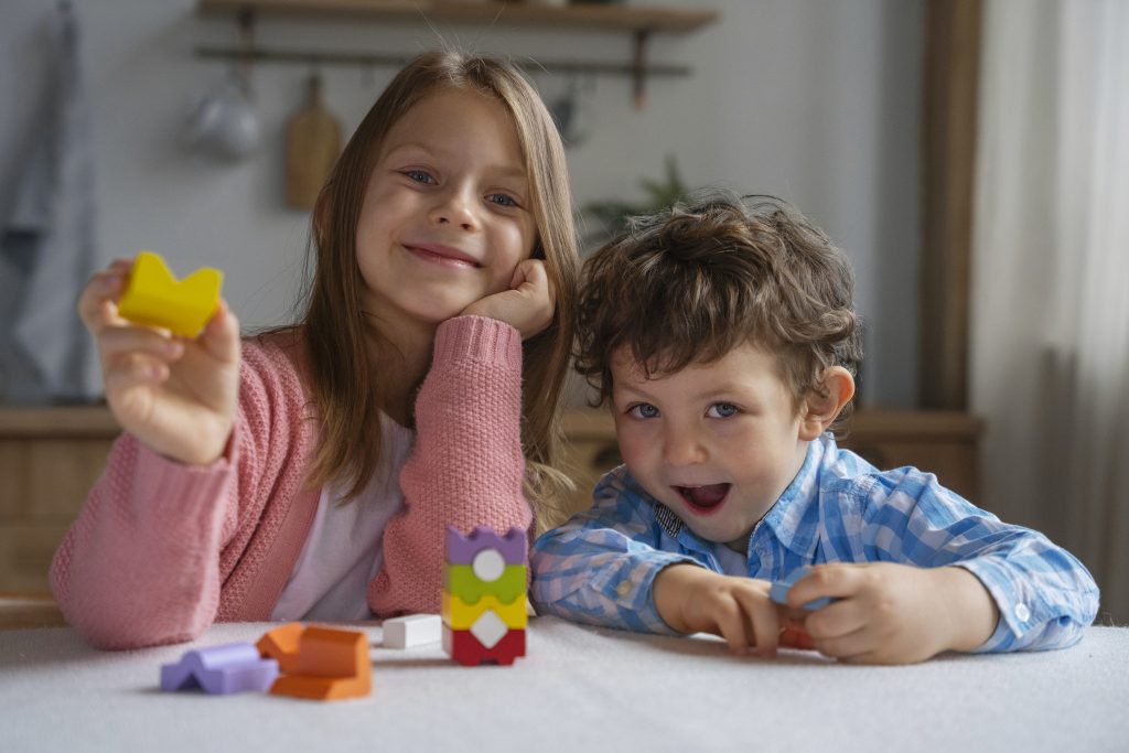 Crianças brincando juntas com blocos coloridos, representando a importância da neurodiversidade no cotidiano entre irmãos.